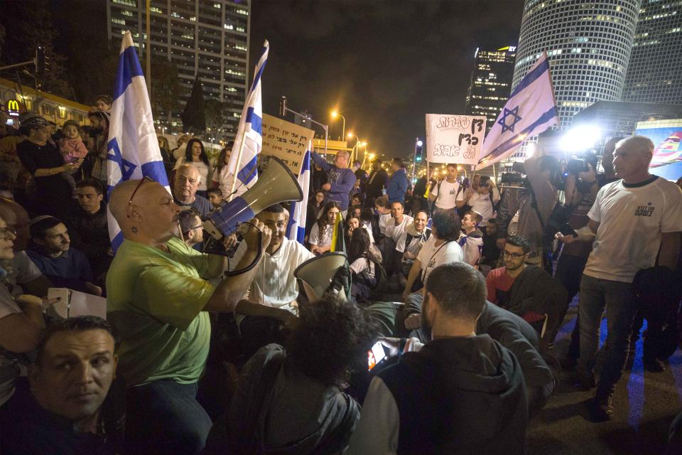 Israeli protesters hold flags and chant slogans during a demonstration against the cease-fire between Israel and Gaza's Hamas in Tel Aviv, Israel, Thursday, Nov. 15, 2018. (AP Photo/Tsafrir Abayov)