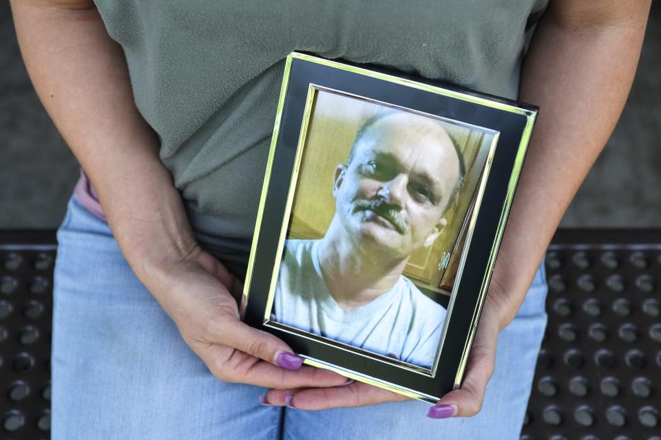 Jennifer Byrum sits holding a portrait of her father, Ricky Lewis, in New Harvest Park, Knoxville, Thursday, May 2, 2024.