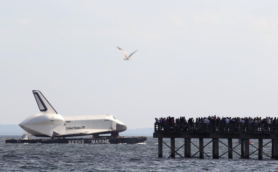 The space shuttle Enterprise is towed past a pier filled with spectators at Coney Island in New York, Sunday, June 3, 2012. The prototype space shuttle that arrived in New York City by air earlier this spring is on the move again, this time by sea, to it's final resting place at the Intrepid Sea, Air and Space Museum on the west side of Manhattan. (AP Photo/Seth Wenig)