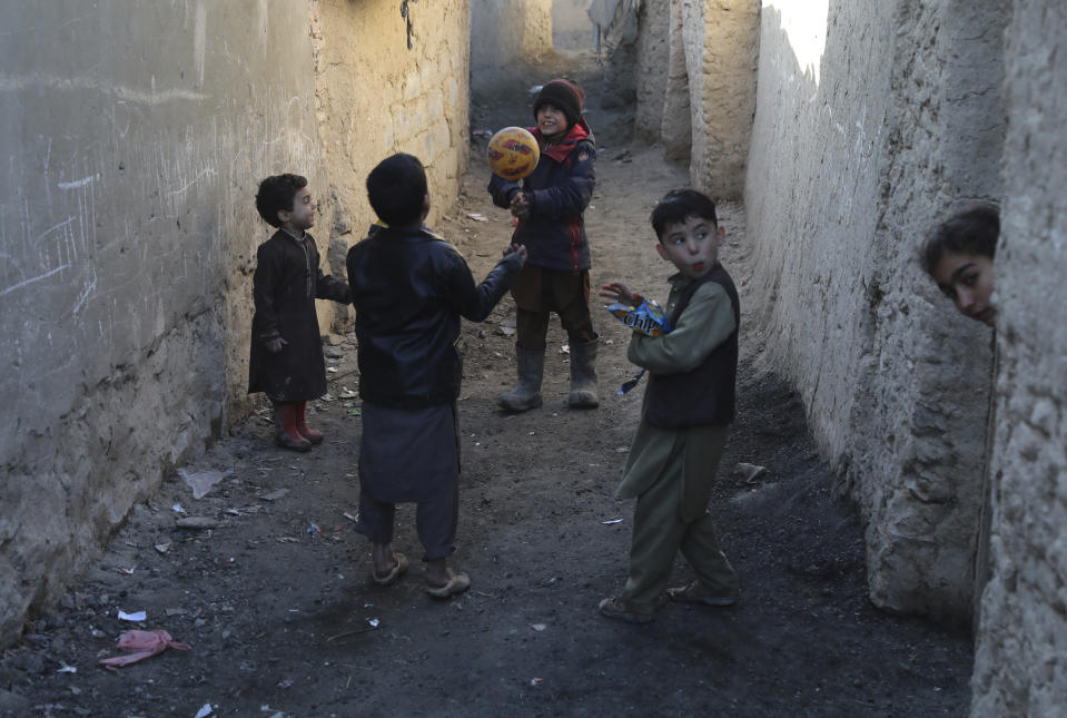 Internally displaced boys play with a ball outside their temporary home in the city of Kabul, Afghanistan, Wednesday, Dec. 30, 2020. Save the Children has warned that more than 300,000 Afghan children face freezing winter conditions that could lead to illness, in the worst cases death, without proper winter clothing and heating. (AP Photo/Rahmat Gul)