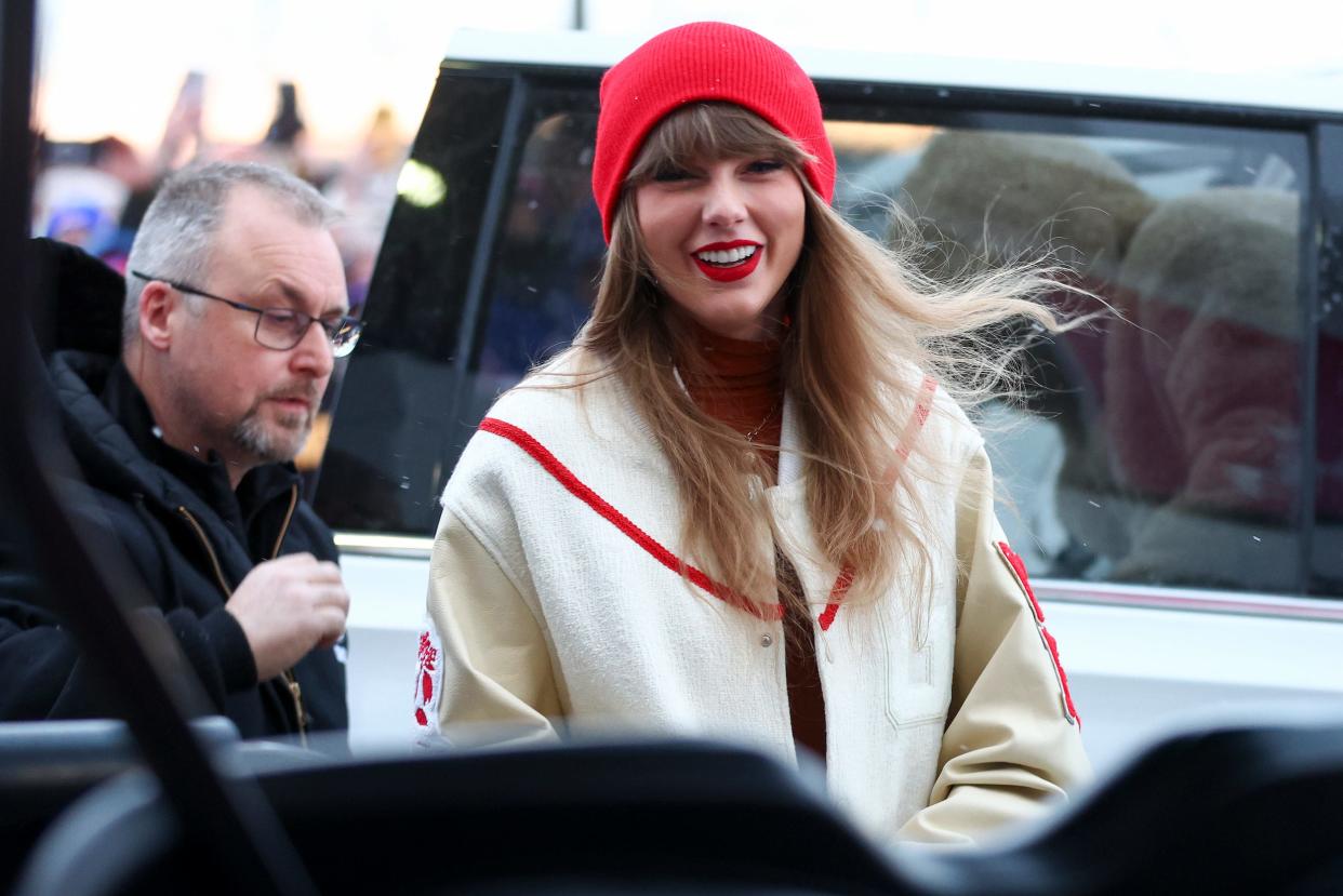 Taylor Swift in a red hat and beige jacket