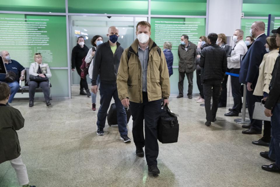 Germany's Enno Lenze, center, and Uwe Keim, center left, both wearing face masks to protect agains coronavirus, enter the hall after arriving at Sheremetyevo airport, outside Moscow, Russia, Thursday, April 15, 2021. The abundance of vaccines in the Russian capital has been drawing in vaccine tourists, not just from other regions, where the wait for a shot is longer, but foreigners, too. A group of Germans traveled to Moscow earlier this month and got their first shots right at their hotel. (AP Photo/Pavel Golovkin)