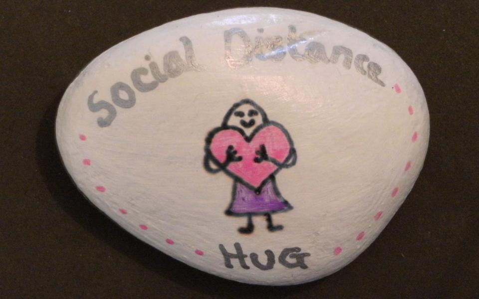 Stone with "social distance hug" written on - PHILIP LLOYD