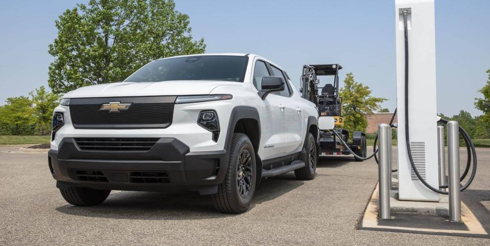 front 34 shot of the silverado ev wt plugged in at a charging station, towing a trailer behind