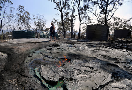 Local resident Jeanette Schwindt inspects her destroyed shed and water tanks after a bushfire swept through the area at Mount Larcom, located west of the township of Gladstone in Queensland, Australia, November 29, 2018. AAP/Dan Peled/via REUTERS