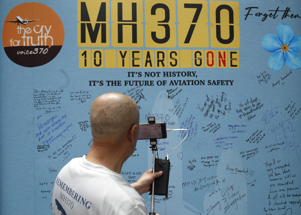 A family member of passenger on board from China of the missing Malaysia Airlines Flight 370 films the message board during the tenth annual remembrance event at a shopping mall, in Subang Jaya, on the outskirts of Kuala Lumpur, Malaysia, Sunday, March 3, 2024. Ten years ago, a Malaysia Airlines Flight 370, had disappeared March 8, 2014 while en route from Kuala Lumpur to Beijing with 239 people on board. (AP Photo/FL Wong)