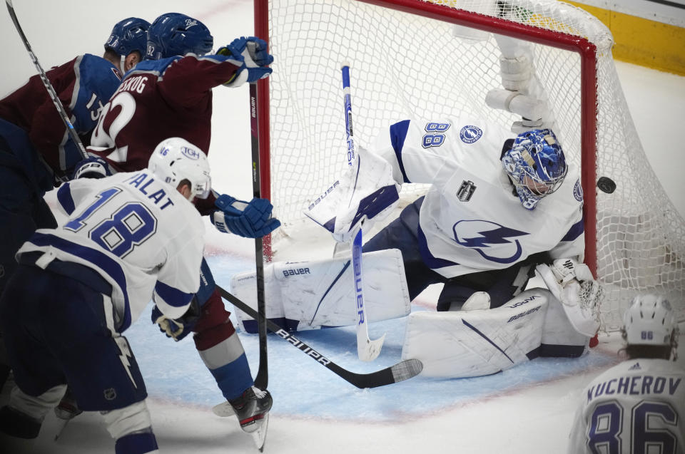 Tampa Bay Lightning goaltender Andrei Vasilevskiy, right, deflects a shot off the stick of Colorado Avalanche left wing Gabriel Landeskog (92) as Tampa Bay left wing Ondrej Palat defends during the third period of Game 5 of the NHL hockey Stanley Cup Final, Friday, June 24, 2022, in Denver. (AP Photo/David Zalubowski)