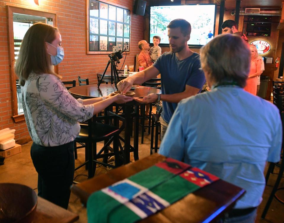 Rev. Kristin Klade, left, hands out communion to a worshiper during the Lutheran-based Kyrie Pub church service in Fort Worth, Texas.