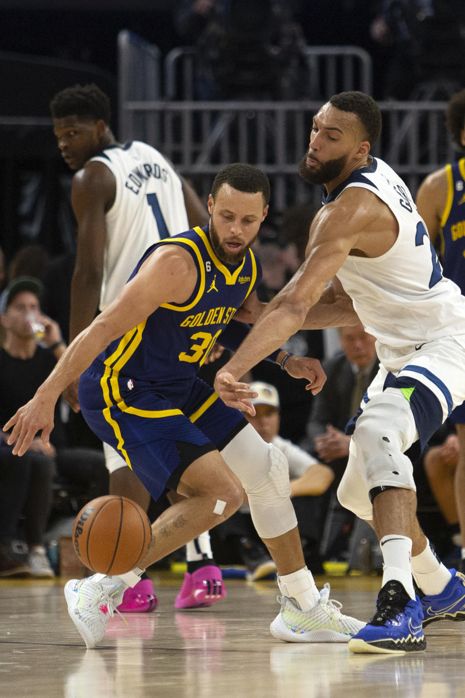 Minnesota Timberwolves center Rudy Gobert, right, tries to knock the ball away from Golden State Warriors guard Stephen Curry (30) during the second quarter of an NBA basketball game, Sunday, March 26, 2023, in San Francisco. (AP Photo/D. Ross Cameron)