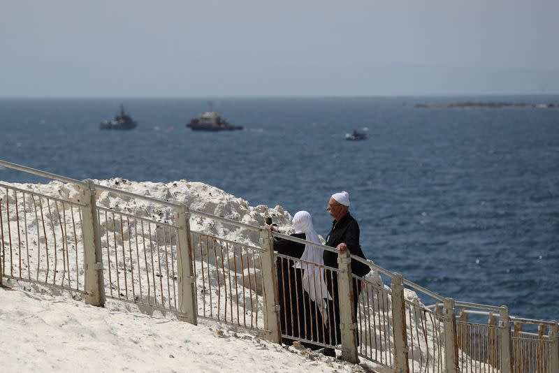 FILE PHOTO: People walk as Israeli navy boats are seen in the Mediterranean Sea as seen from Rosh Hanikra, close to the Lebanese border, northern Israel May 4, 2021.