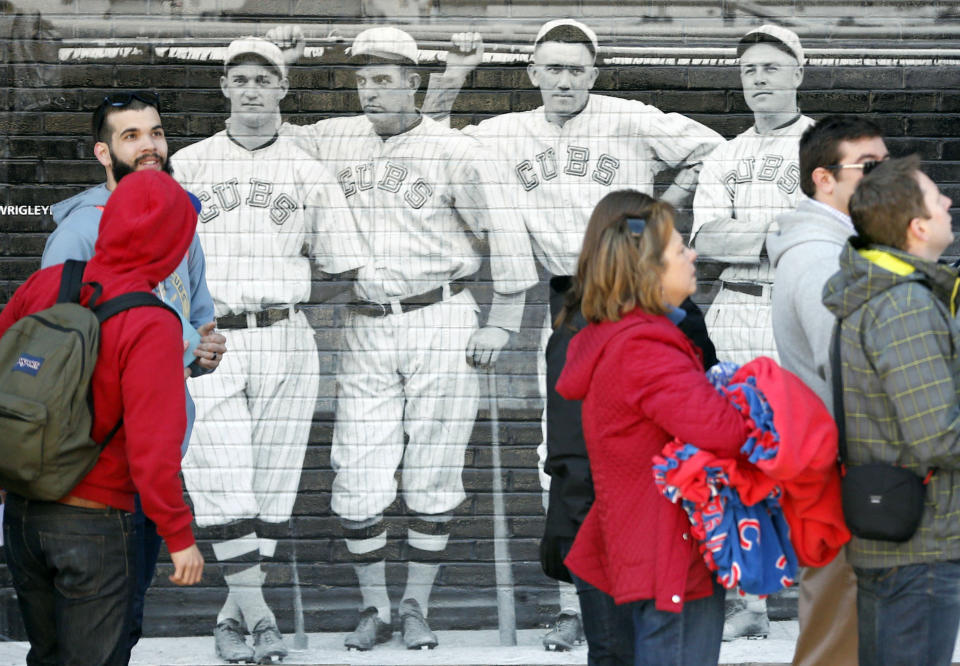 Baseball fans walk past a mural of four 1918 Chicago Cubs' players as they enter Wrigley Field on the 100th anniversary of the first baseball game at the park, before a game between the Arizona Diamondbacks and Chicago Cubs, Wednesday, April 23, 2014, in Chicago. (AP Photo/Charles Rex Arbogast)