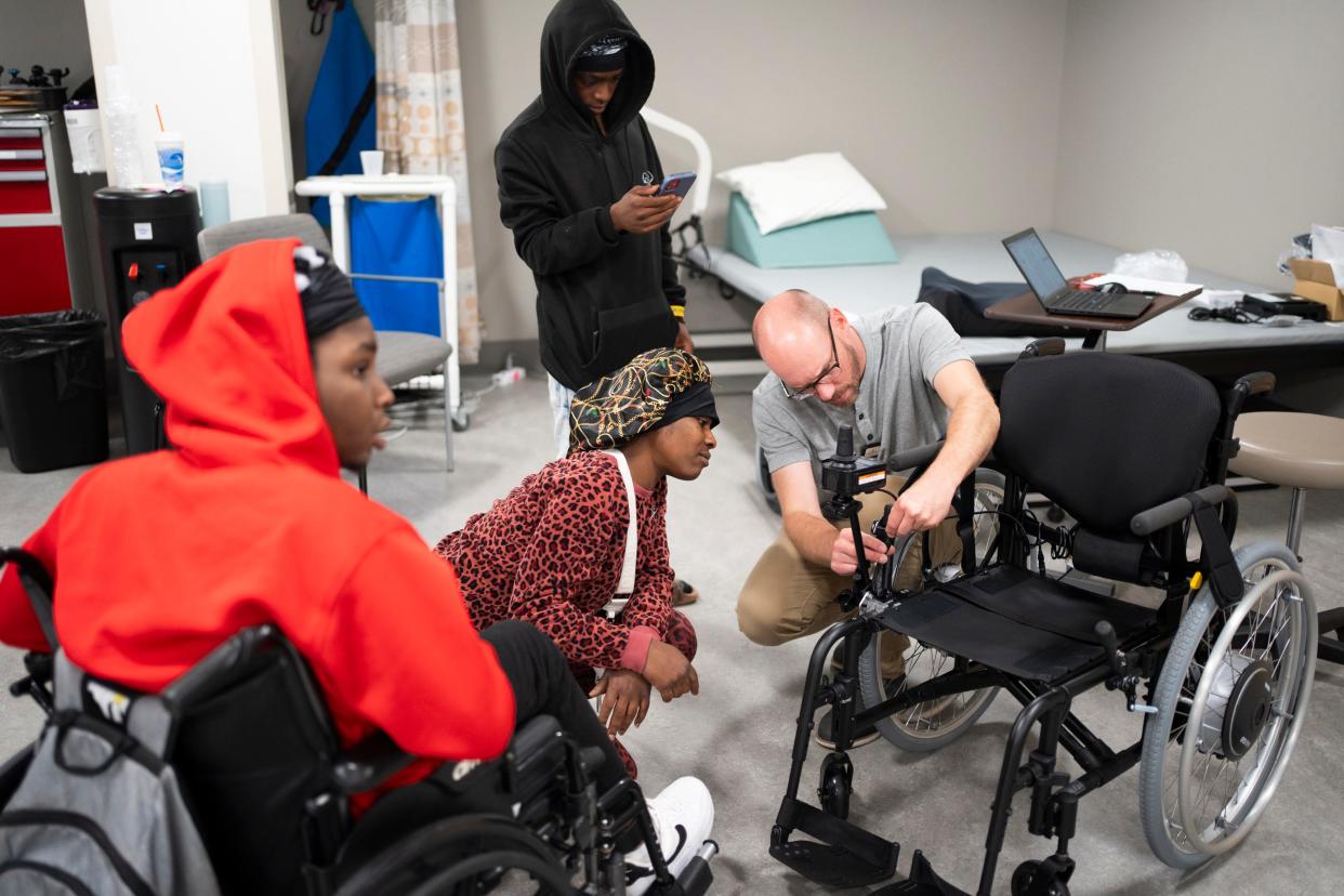 Mary Washington looks at the features of the new custom wheelchair for her son Damarion Allen, left.