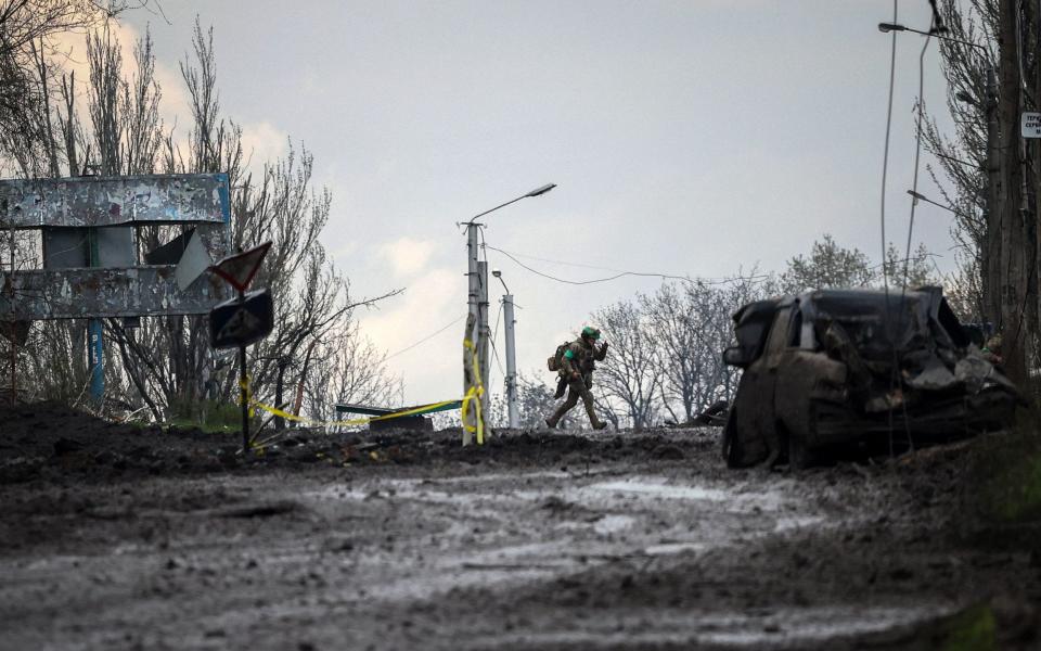 Ukrainian serviceman runs for cover from shelling across a street in the frontline town of Bakhmut - ANATOLII STEPANOV/AFP