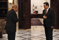 Lebanese Prime Minister Hassan Diab, right, receives French Foreign Minister Jean-Yves Le Drian, as they don't shake hands to help prevent the spread of the coronavirus, at the Government House, in Beirut, Lebanon, Thursday, July 23, 2020. Le Drian is in Lebanon for two days visit to meet with Lebanese officials and top politician leaders. (AP Photo/Hussein Malla)