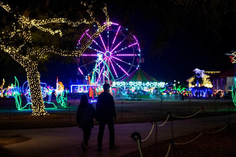 A couple strolls through Jones Park during the Harbor Lights Winter Festival in Gulfport on Thursday, Dec. 2, 2021.
