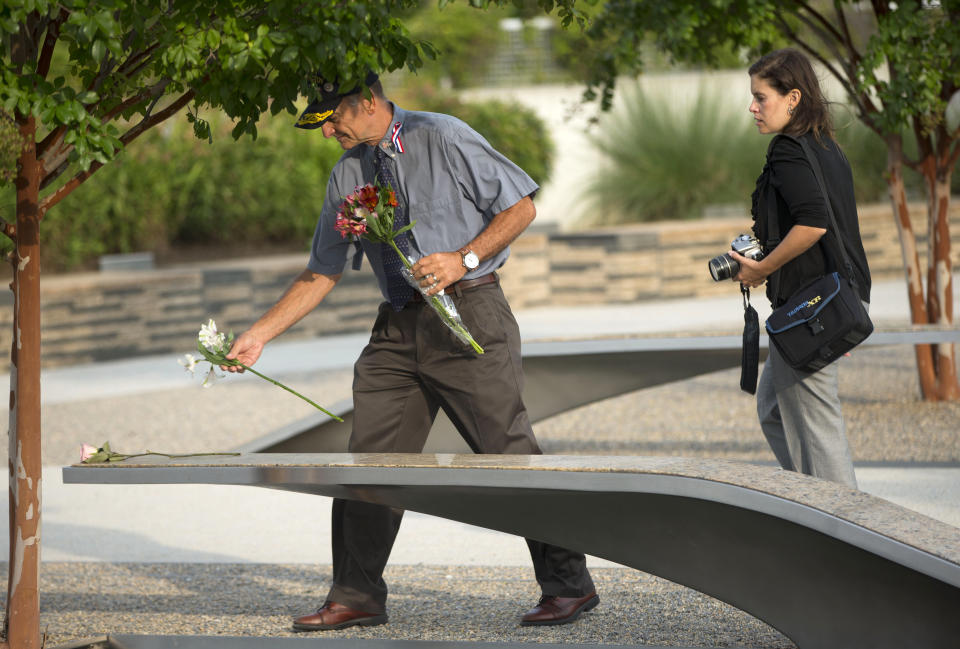 A man places a flower on one of the benches of the Pentagon Memorial at the at the Pentagon, Thursday, Sept. 11, 2014. President Barack Obama will attend the  wreath laying later this morning to to mark the 13th anniversary of the 9/11 attacks. (AP Photo/Pablo Martinez Monsivais)