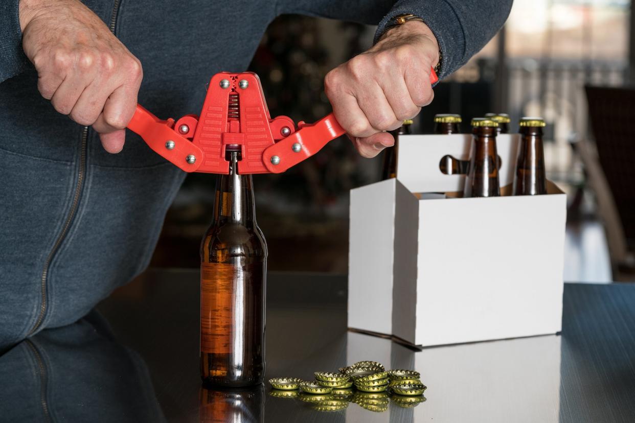 man using capper to put metal caps on beer bottle