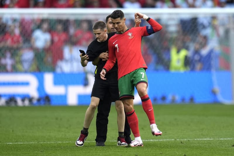 A pitch invader attempts to get a photo with Portugal's Cristiano Ronaldo during the UEFA Euro 2024 Group F soccer match between Turkey and Portugal at the Signal Iduna Park in Dortmund. Nick Potts/PA Wire/dpa