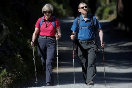 FILE PHOTO: Britain's Prime Minister Theresa May walks in a forest with her husband Philip at the start of a summer holiday in the Alps, in Switzerland