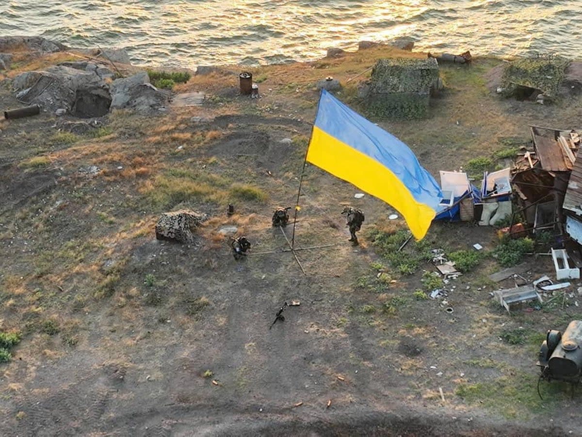 Ukrainian service members install a national flag on Snake Island after recapturing it (via REUTERS)