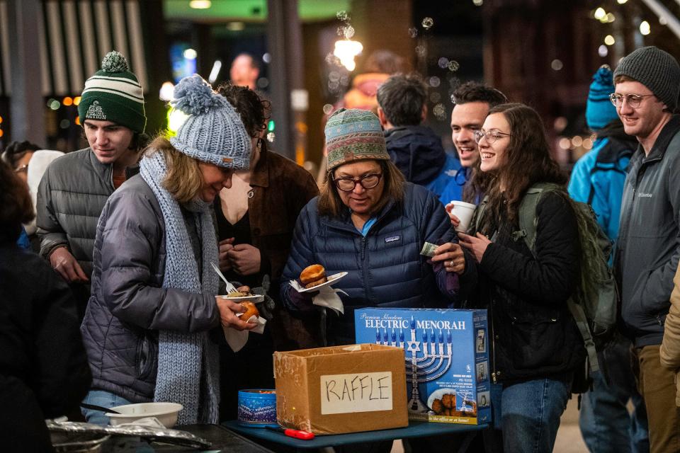 People in line socialize as they get food during a Menorah lighting ceremony in Old Town in Fort Collins Monday.