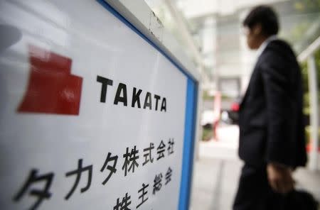 A man walks past a sign board of Japanese auto parts maker Takata Corp's Annual General Meeting in Tokyo June 26, 2014. REUTERS/Yuya Shino