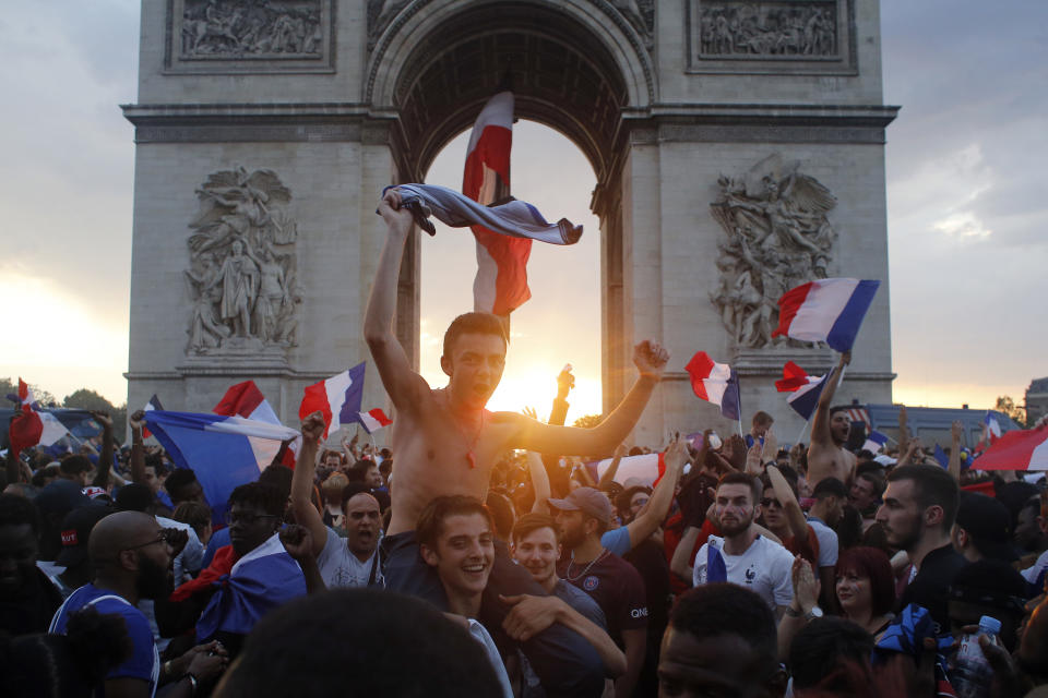 FILE - In this Sunday, July 15, 2018 file photo, people gather around the Arc de Triomphe in Paris, to celebrate France's World Cup victory over Croatia. On Friday, July 23, 2021, The Associated Press reported on a photo of a blond woman with a flag atop the Arc de Triomphe circulating online, incorrectly asserting it shows recent protests in Paris over the government’s latest coronavirus measures. But the photo shows celebrations in Paris in July 2018 after France won the World Cup, not a recent protest. (AP Photo/Thibault Camus, File)