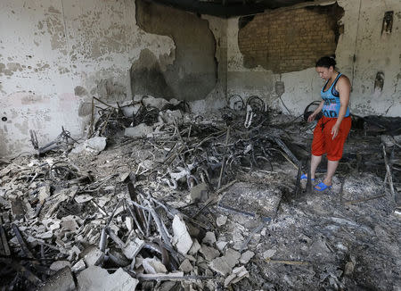 A woman stands near charred debris in a bicycle store after what locals say was overnight shelling by Ukrainian forces, in the eastern Ukrainian town of Slaviansk June 9, 2014. REUTERS/Gleb Garanich