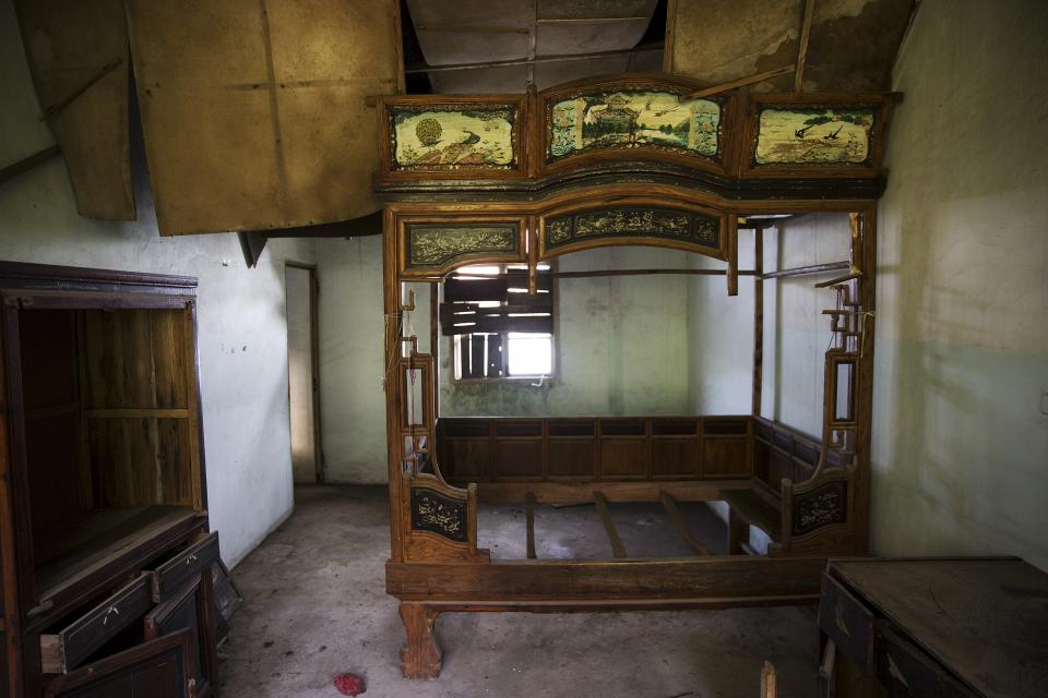A bed and other furniture are left inside a room of a small apartment at the abandoned fishing village of Houtouwan on the island of Shengshan July 26, 2015. (REUTERS/Damir Sagolj)