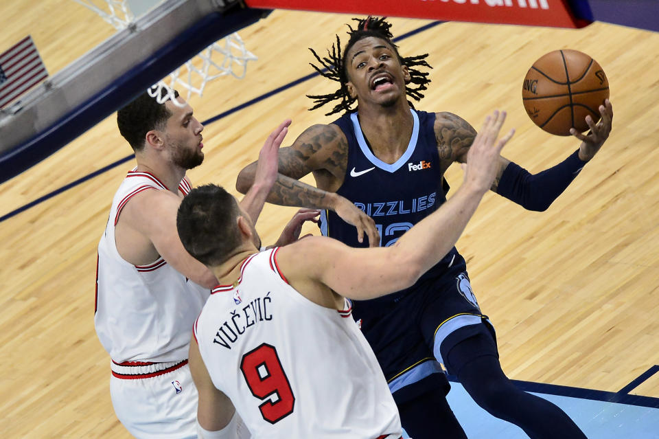 Memphis Grizzlies guard Ja Morant (12) handles the ball against Chicago Bulls center Nikola Vucevic (9) guard Zach LaVine in the second half of an NBA basketball game Monday, April 12, 2021, in Memphis, Tenn. (AP Photo/Brandon Dill)