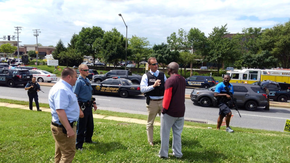 Police officers talk to a man outside the scene.&nbsp;