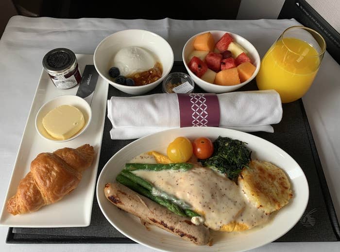 Omelette, hollandaise sauce, potato rosti, asparagus, sausage, and tomatoes. A side of croissant, butter, jam, fresh fruit, yogurt parfait, and orange juice. 