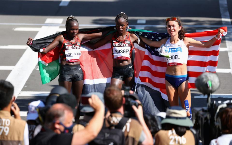 Gold medallist Peres Jepchirchir of Kenya, silver medallist Brigid Kosgei of Kenya and bronze medallist Molly Seidel of the United States posing holding their flags. - REUTERS/Kim Hong-Ji