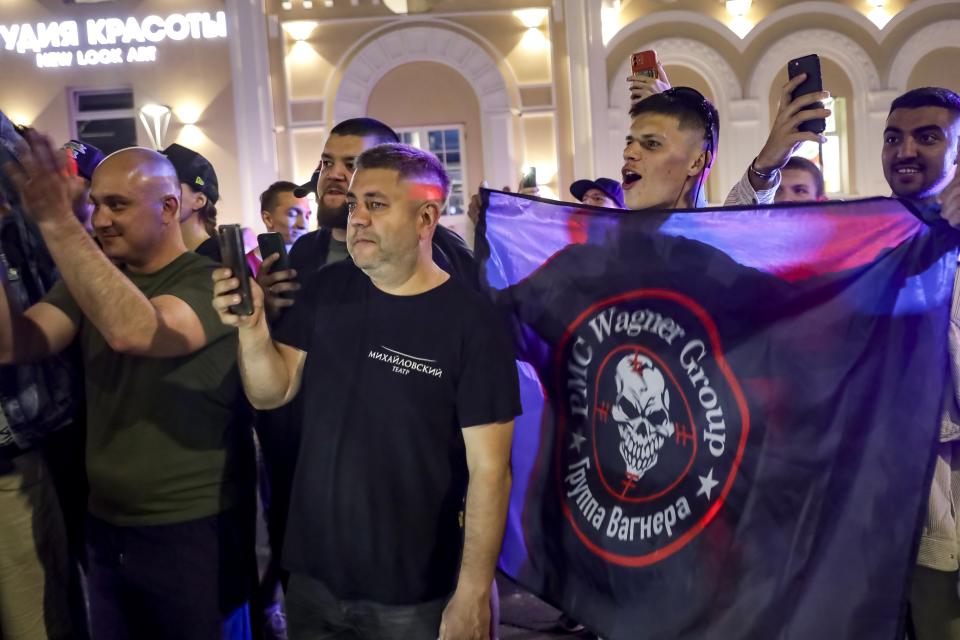 People shout and wave a flag of the Wagner Group military company to servicemen prior to their leaving an area at the headquarters of the Southern Military District in Rostov-on-Don, Russia, Saturday, June 24, 2023. Kremlin spokesman Dmitry Peskov said that Yevgeny Prigozhin's troops who joined him in the uprising will not face prosecution and those who did not will be offered contracts by the Defense Ministry. After the deal was reached Saturday, Prigozhin ordered his troops to halt their march on Moscow and retreat to field camps in Ukraine, where they have been fighting alongside Russian troops. (AP Photo)