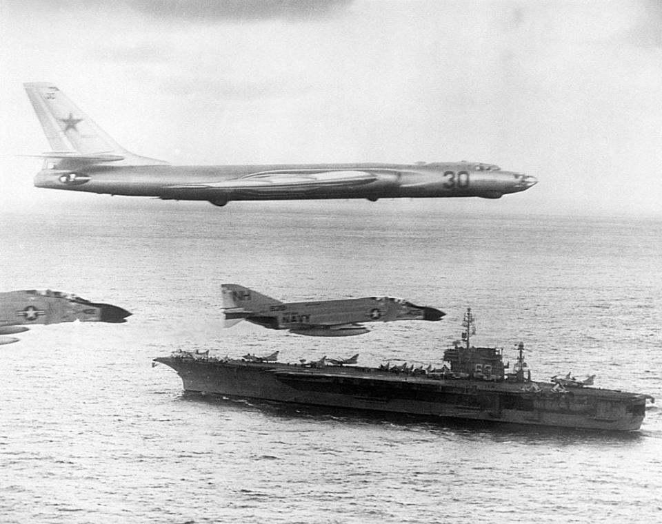 A Russian-made Tupolev TU-16 Badger-A surveillance bomber flies with U. S. Navy escort fighters over the attack carrier USS Kitty Hawk during Cold War activities over the North Pacific Ocean in January of 1963