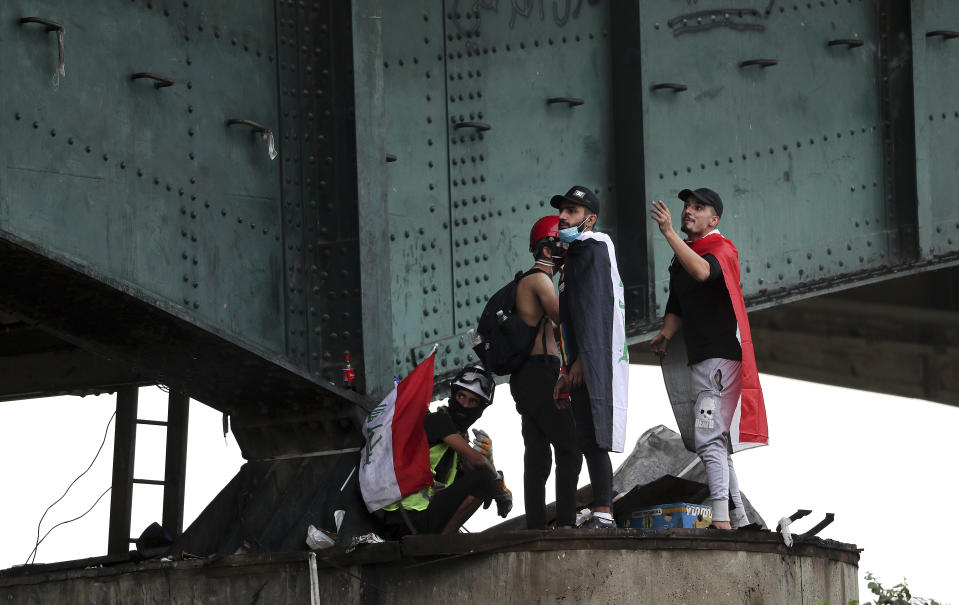 Protesters stand under the Joumhouriya Bridge, that lead to the Green Zone where many government offices and embassies are located, during ongoing anti-government protests in Baghdad, Iraq, Sunday, Nov. 3, 2019. (AP Photo/Hadi Mizban)