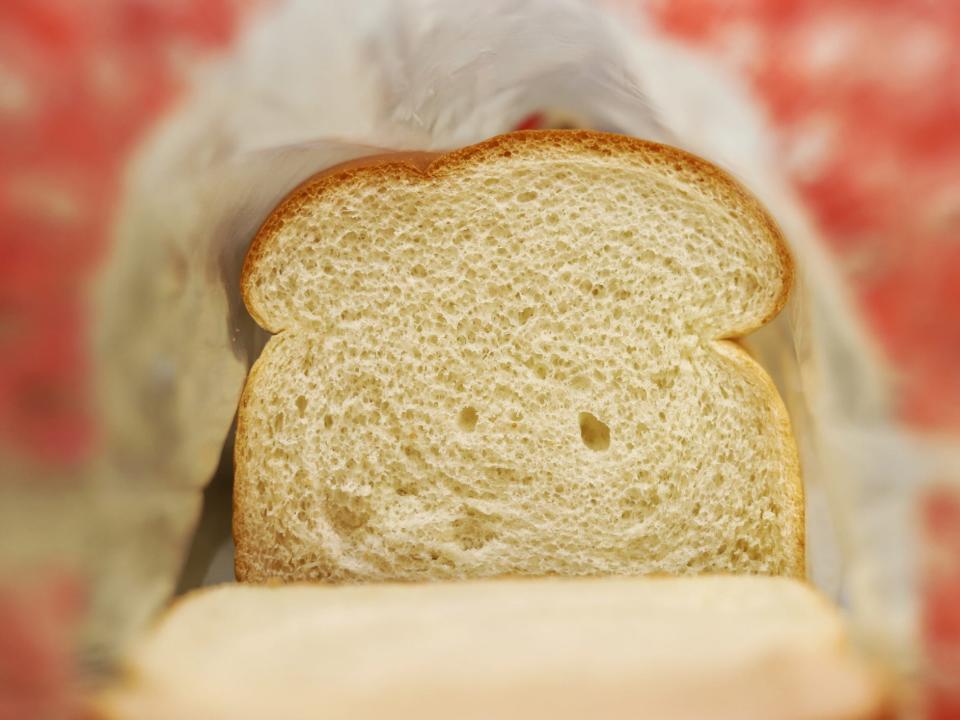 a slice of white bread, viewed from a close angle inside a plastic bread bag