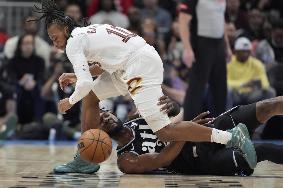 Cleveland Cavaliers guard Darius Garland (10) and Atlanta Hawks forward Bruno Fernando (24) battle for the ball during the first half of an NBA basketball game Wednesday, March 6, 2024, in Atlanta. (AP Photo/John Bazemore)