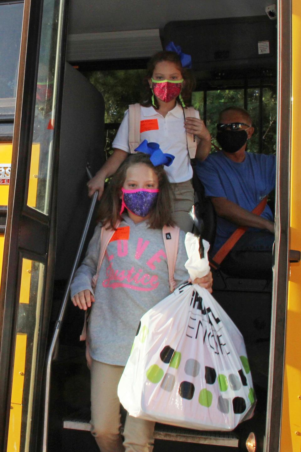 Masked students arrive at Newton County Elementary School in Decatur, Miss., on Aug. 3.  Thousands of students across the nation are set to resume in-person school for the first time since March. Parents have to balance the children's need for socialization and instruction that school provides with the risks of coronavirus.