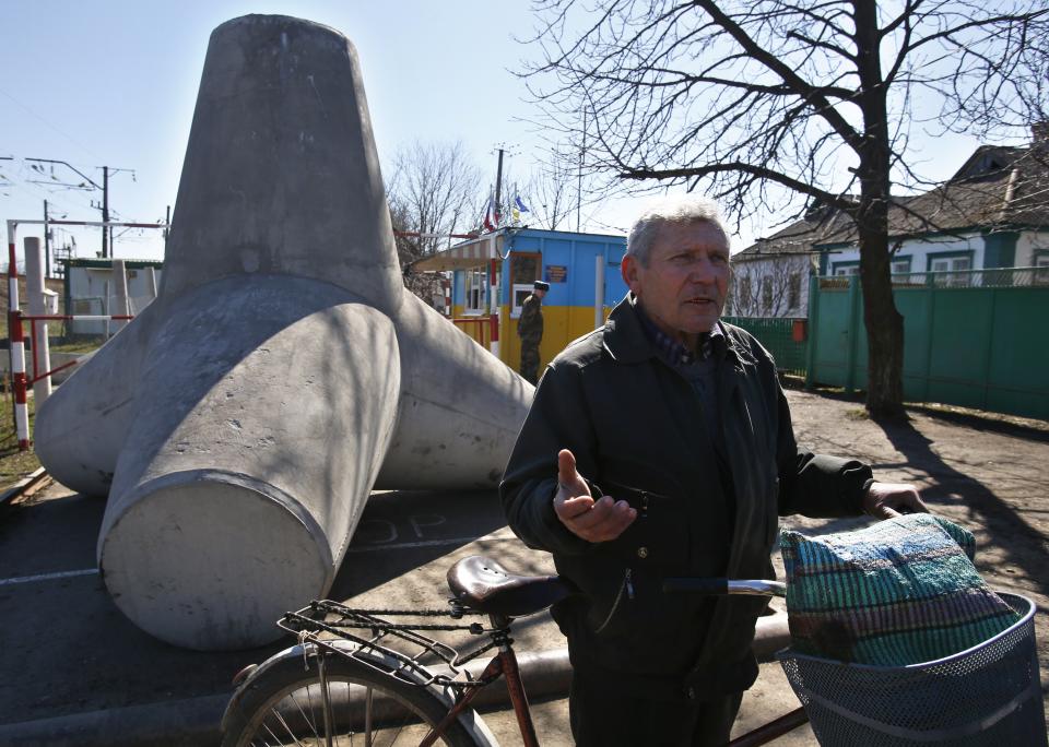 In this photo taken Monday, March 24, 2014, Russian citizen, retired doctor Nikolai Chernyshev speaks after crossing crossing a Ukrainian-Russian border in the village of Vyselki, eastern Ukraine. Ever since the 1991 breakup of the Soviet Union, the village of Vyselki has been split between Ukraine and Russia. For years its residents have continued to live together peacefully, doing most of their shopping in one country and paying their electricity bills in another. But after Russia seized the Crimean Peninsula from Ukraine, the Ukrainian villagers fear a further incursion of Russian troops, while the Russians say they would welcome their protection against the new pro-Western government in Kiev. (AP Photo/Sergei Grits)