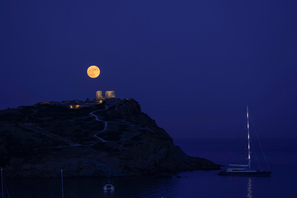 The strawberry full moon rises behind the ancient marble temple of Poseidon at Cape Sounion, about 45 miles south of Athens, on Thursday, June 24, 2021.