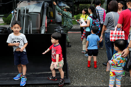 Children react around a military vehicle during a public fair which displays military equipments, in Taipei, Taiwan September 29, 2018. Picture taken September 29, 2018. REUTERS/Tyrone Siu