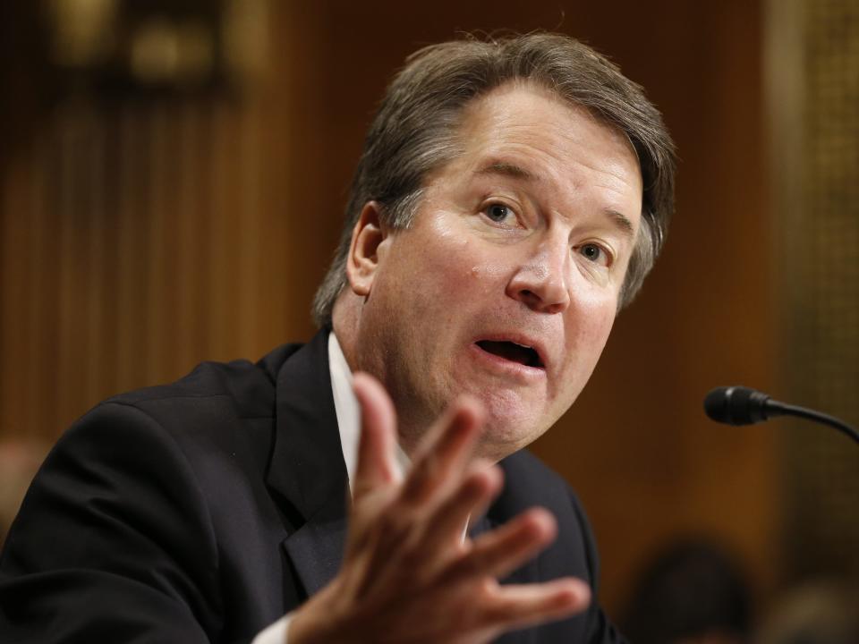 Brett Kavanaugh raises his arm while talking.