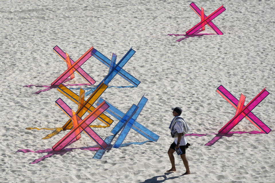 A man walks past an installation titled "No Colour In War" by Emryn Ingram-Shute as artists prepare for the open of the annual Sculpture by the Sea exhibition along the coast in Sydney, Thursday, Oct. 19, 2023. (AP Photo/Rick Rycroft)