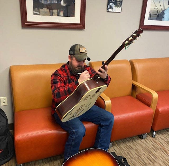 Ben Newcomer signs the graduation guitar for Guitar for Vets at the South Bend Vet Center. Everyone signs the guitar when they complete 10 classes and receive a free guitar.