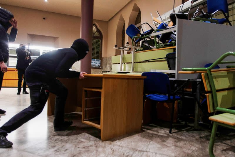 A demonstrator in support of rap singer Pablo Hasel uses a table to set up a barricade against a door of the rectory of Lleida University