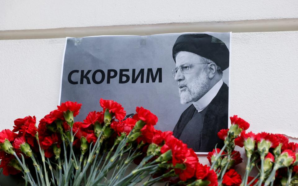 A view shows flowers outside the Iranian embassy placed to pay tribute to Iran's President Ebrahim Raisi in Moscow. The placard reads: "We mourn".