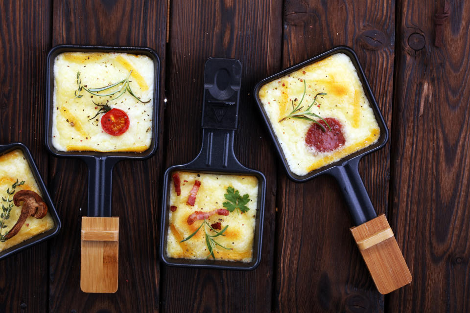 Delicious traditional Swiss melted raclette cheese on diced boiled or baked potato served in individual skillets with salami.