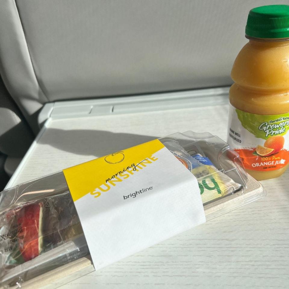 bottle of orange juice and package of cheese, apple slices, and crackers on train table