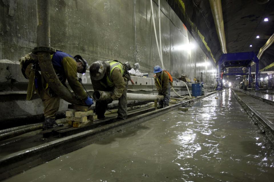 FILE - In this Feb. 3, 2010 file photo, a sand hog works inside the massive cavern for the new 34th Street Station in New York that was carved out by giant tunnel boring machines. On Monday, July 23, 2012 the last of the 200-ton tunnel boring machines finished its mission digging 13 miles of new train tubes deep beneath New York City. The seven machine fleet bored through bedrock and created 16 new tunnels in 4 ½ years of digging. (AP Photo/Mary Altaffer, File)